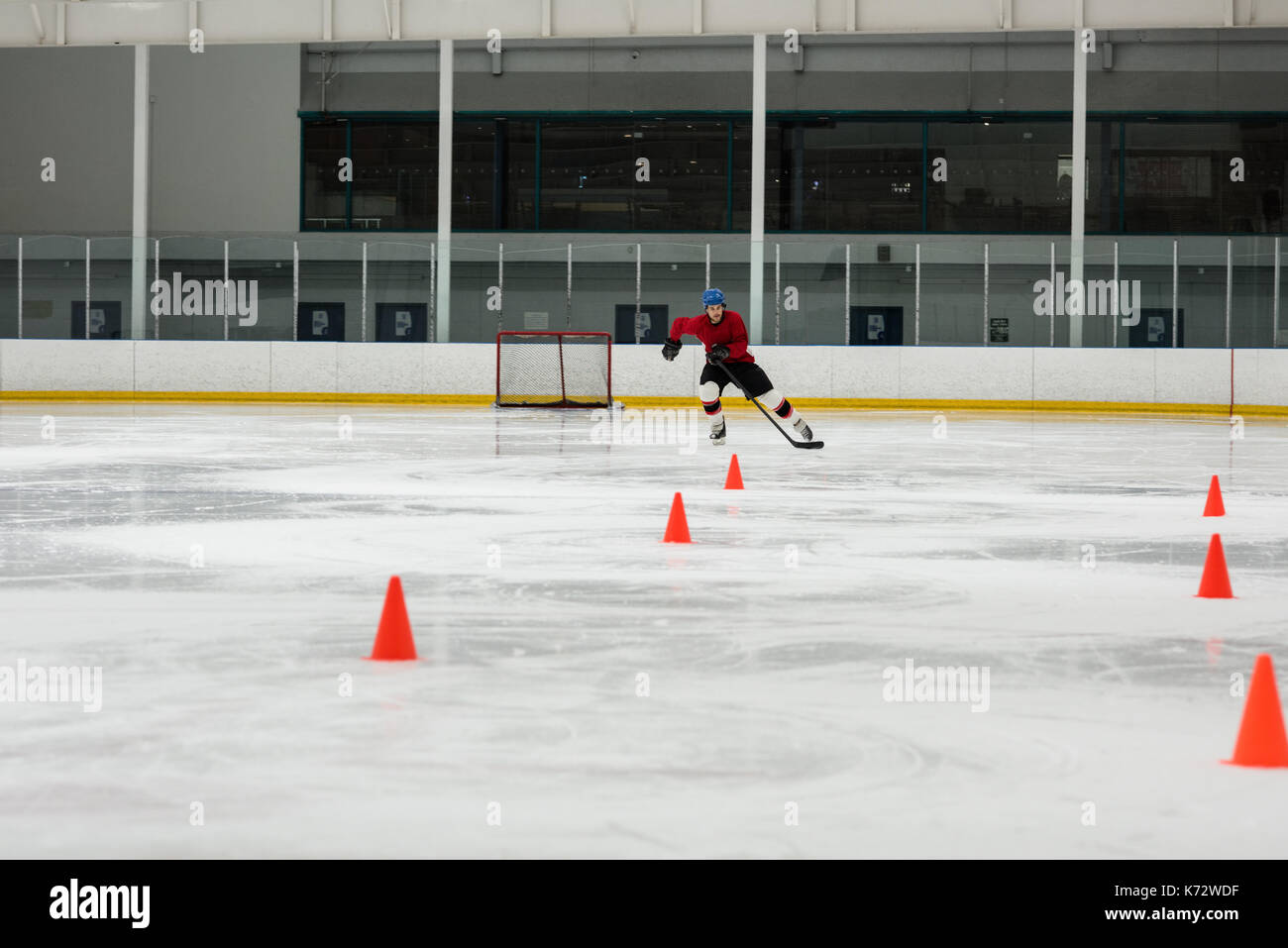 Männliche Eishockey Spieler üben Bohrer durch sport training Kegel an der Eisbahn Stockfoto