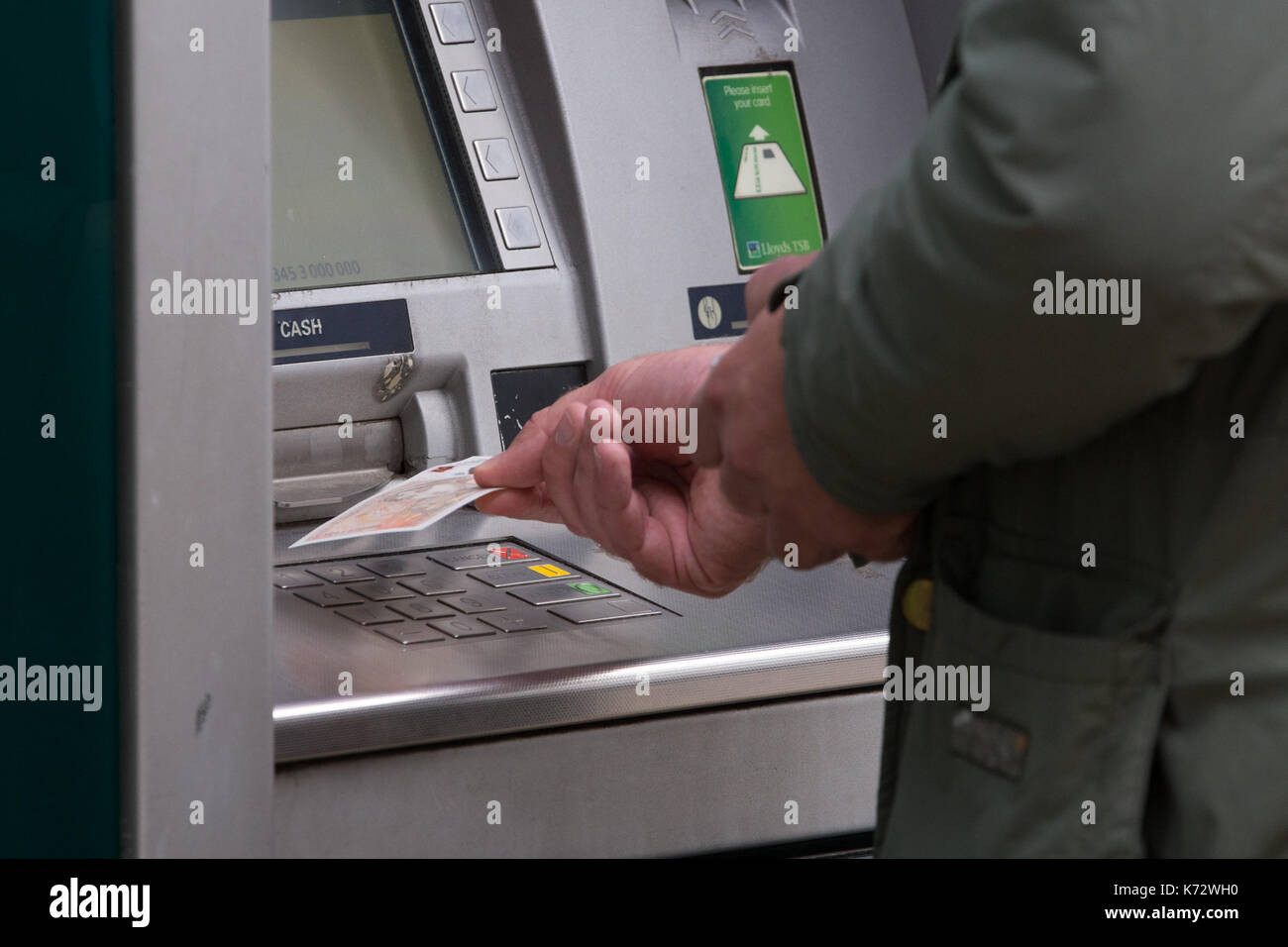 Ein Mann zieht sich die neuen zehn Pfund Hinweis mit Jane Austen, am Bankautomaten auf Birmingham High Street. Stockfoto