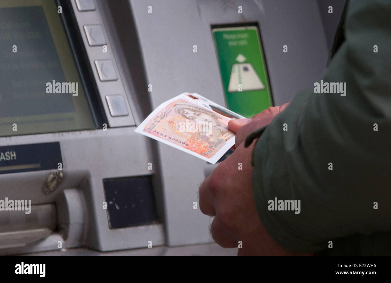 Ein Mann zieht sich die neuen zehn Pfund Hinweis mit Jane Austen, am Bankautomaten auf Birmingham High Street. Stockfoto