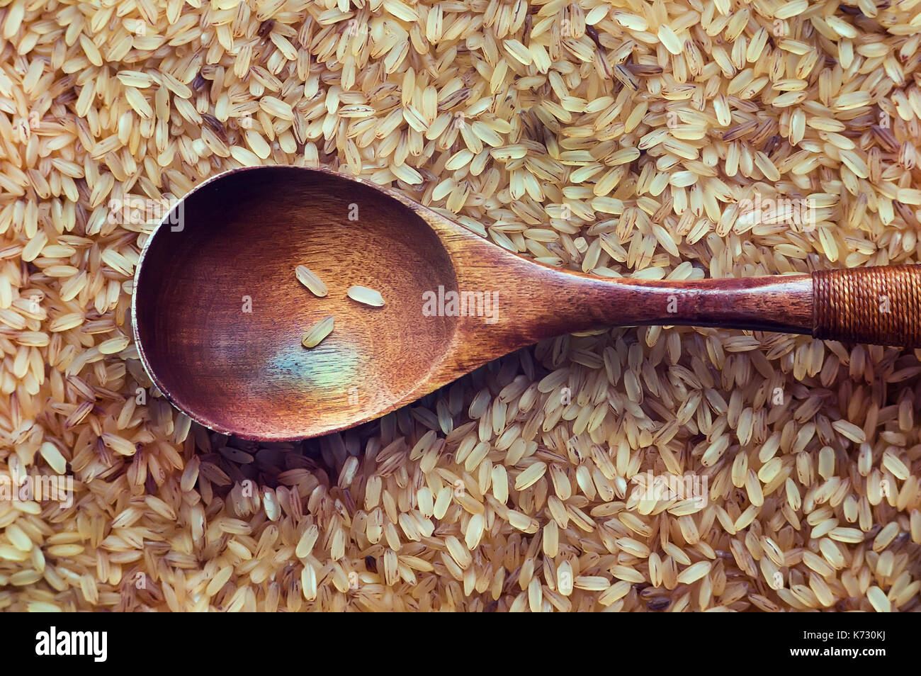 Essen Hintergrund. brauner Reis in einem Holzlöffel close-up. Ansicht von oben. Billige Lebensmittel für die Hungernden und armen Regionen Südostasiens. Stockfoto