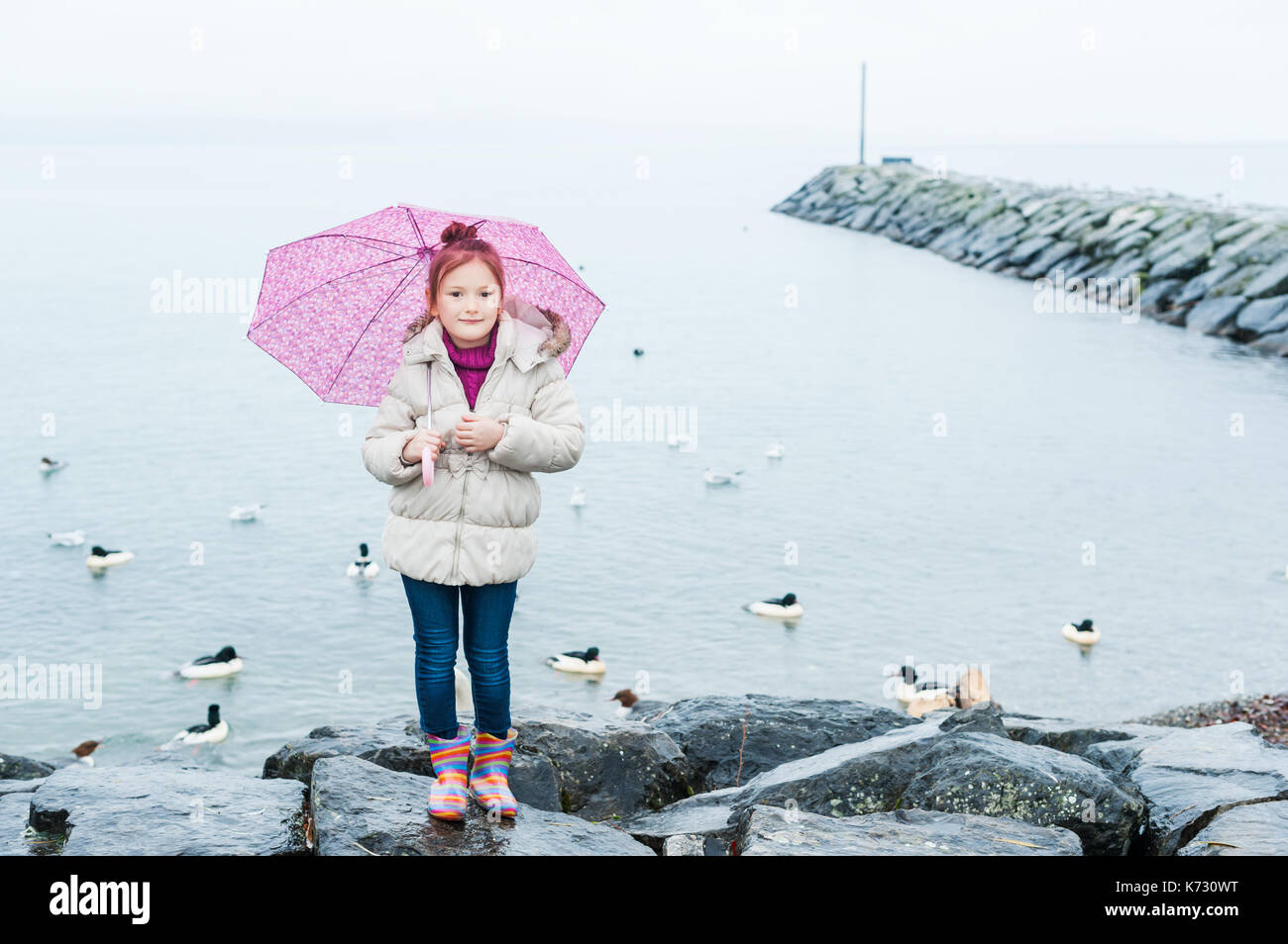 Nahaufnahme Portrait von einem kleinen Mädchen mit rosa Regenschirm unter dem Regen Stockfoto