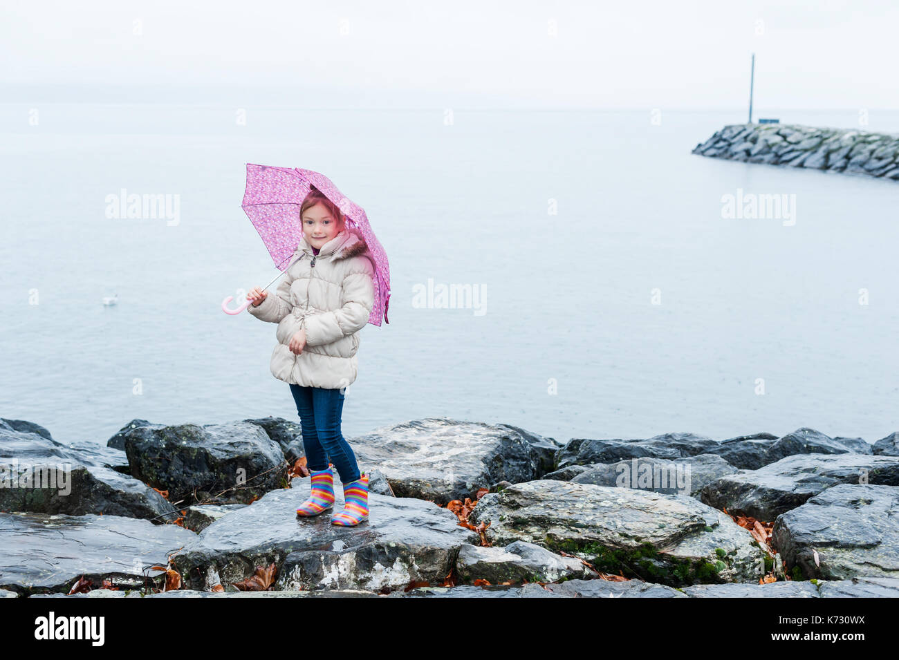 Nahaufnahme Portrait von einem kleinen Mädchen mit rosa Regenschirm unter dem Regen Stockfoto