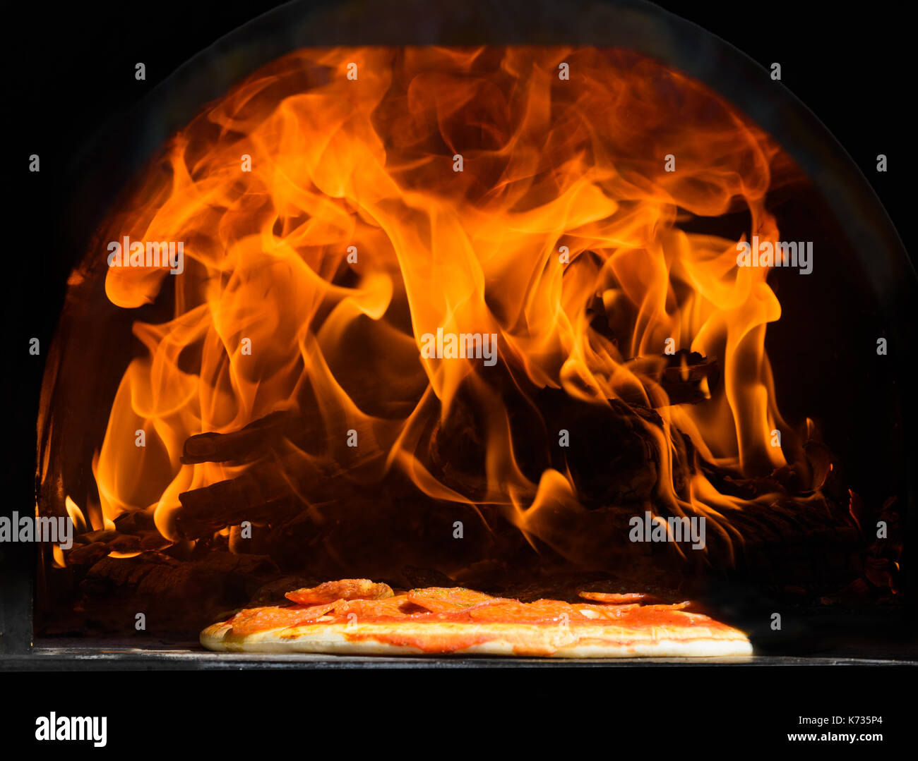 Pizza Kochen als lames Sprung von einer flammenden in einem Metallgehäuse Holzofen anmelden Stockfoto