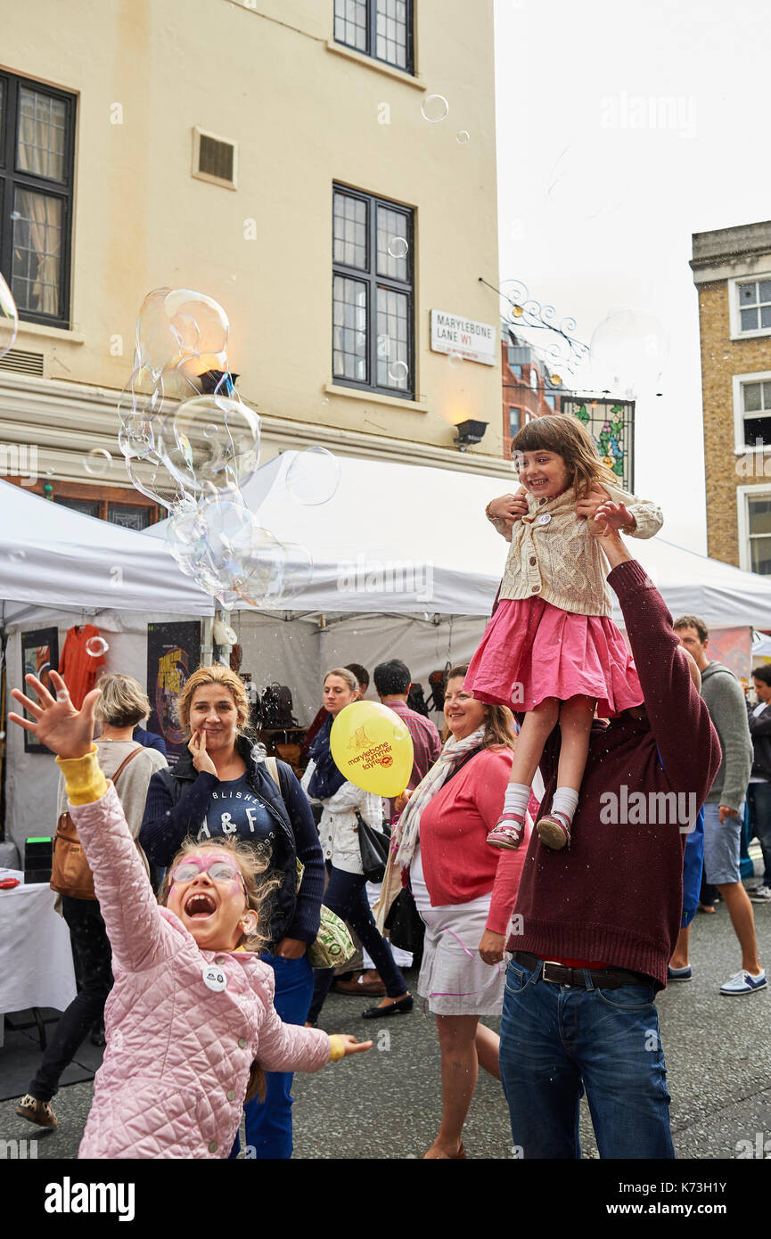Kinder und Erwachsene Eltern spielen mit Luftblasen Spaß auf der London Street Fair fayre UK Großbritannien Stockfoto