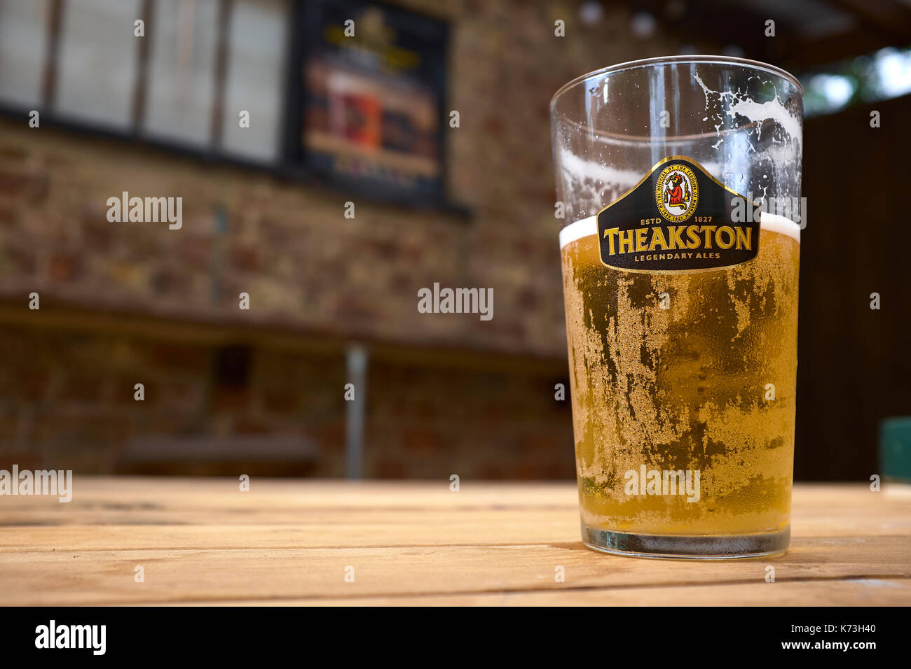 Eine halb fertige pint Theakston's Ale Bier auf einem Holztisch, in einem Yorkshire pub Public House, Vereinigtes Königreich. Stockfoto