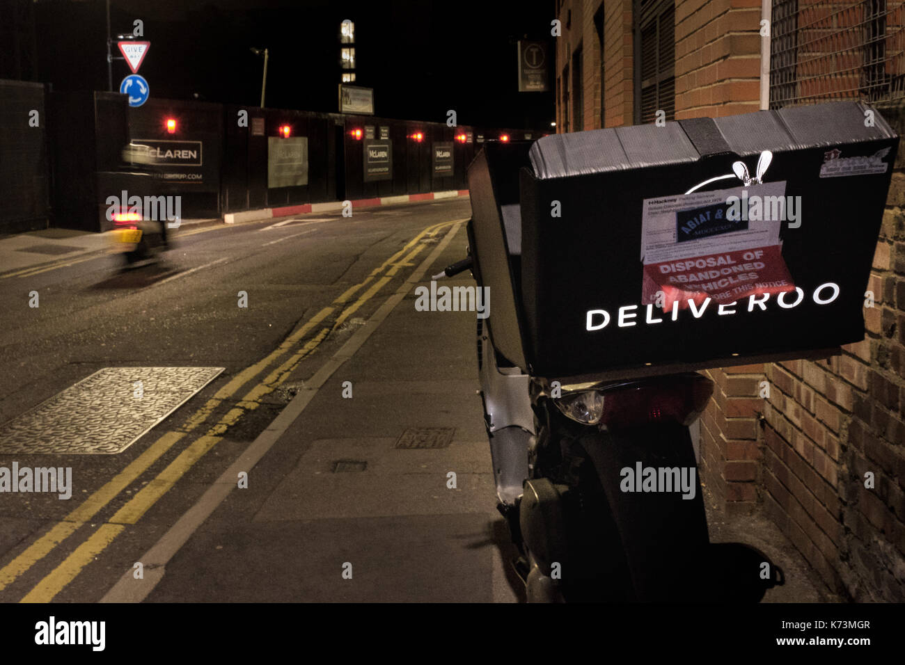 Ein Moped mit einem Deliveroo Essen courier Kasten auf der Rückseite legt in der Hoxton/Shoreditch Bereich Nord-ost London verlassen, mit einem Rat Entsorgung von zurueckgelassenen Fahrzeuge 'Warnung auf sie hatte. 14. September 2017. Stockfoto