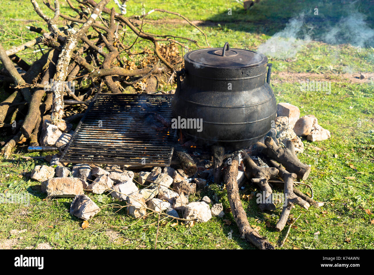 Kochen über dem offenen Feuer mit einem Metall Kochtopf sanft Garen auf einem Holz brennen Lagerfeuer Stockfoto