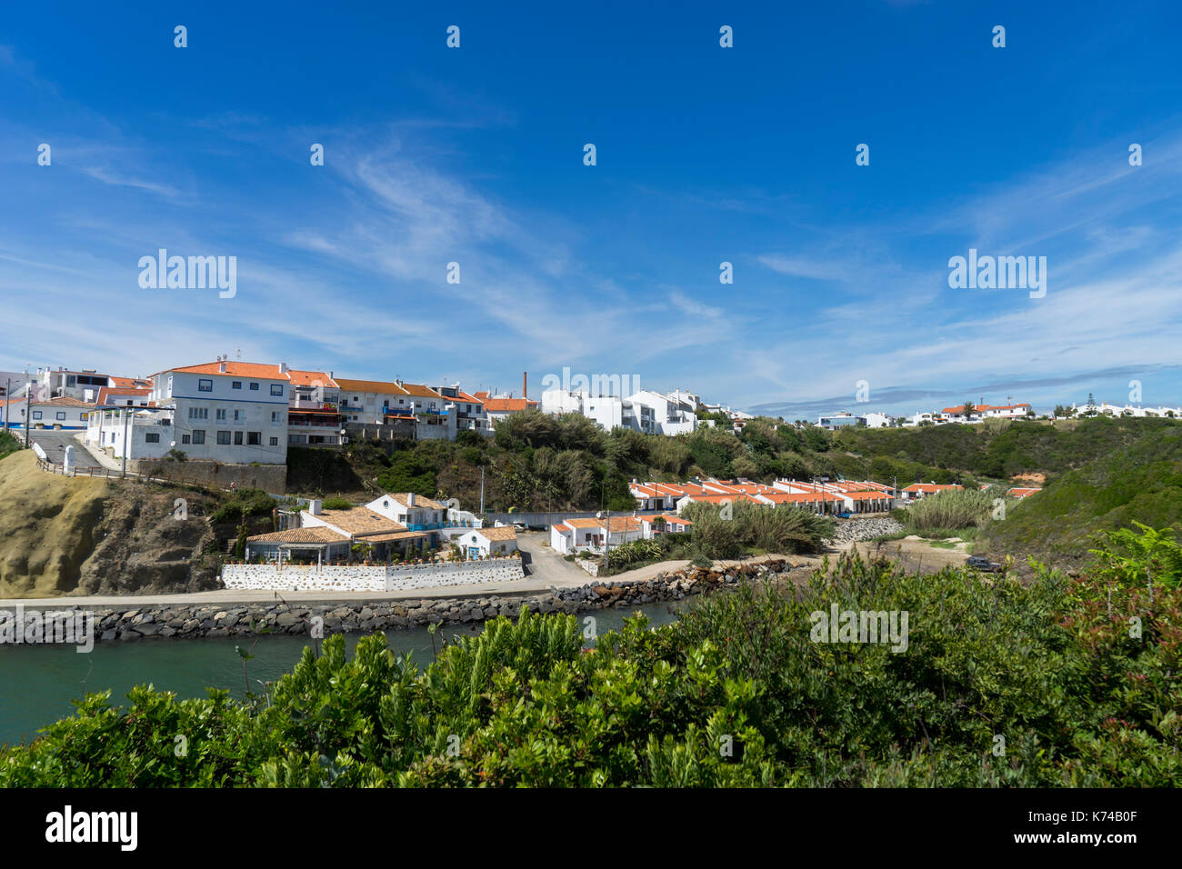 Blick über die kleine Bucht zu den Häusern auf der Spitze des Hügels in Porto Covo, Setúbal, Portugal Stockfoto
