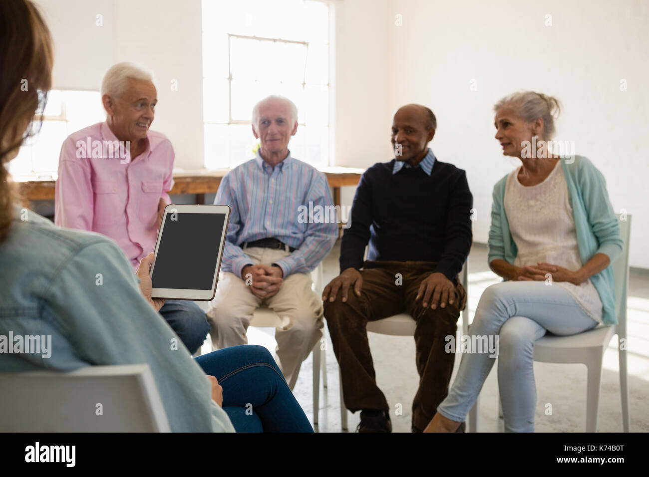 Frau mit Tablet-PC während der Diskussion mit ältere Erwachsene in der Kunst Klasse Stockfoto