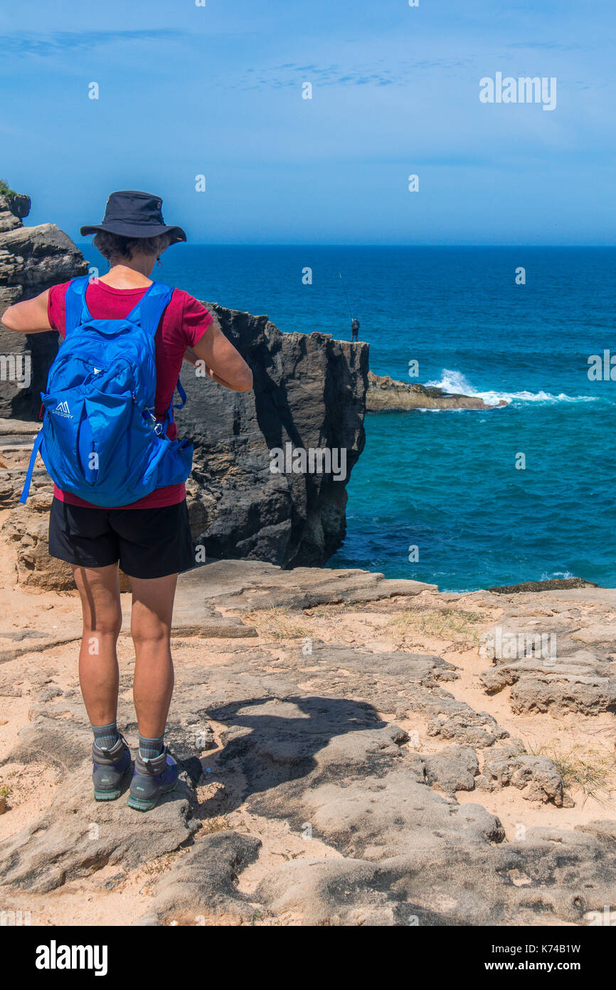 Eine weibliche Wanderer steht auf den Klippen mit Blick aufs Meer entlang der Fishermans Trail in der Nähe von Vila Nova de Milfontes Portugal zu. Einsame Angler in der Ferne Stockfoto