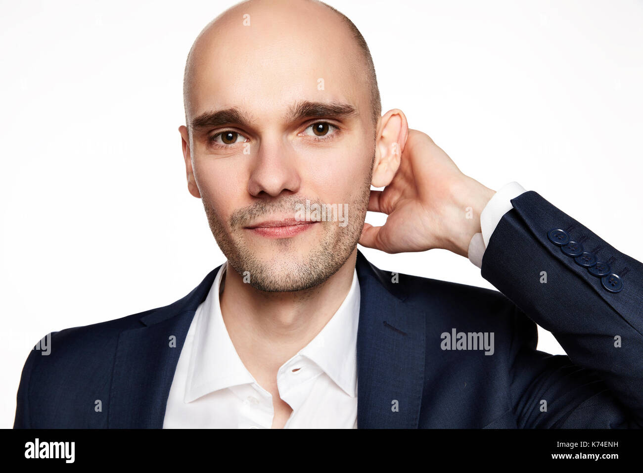 Nahaufnahme Porträt einer stattlichen glatzköpfige Mann seinen Kopf streicheln. Er lächelt. Weißer Hintergrund. Horizontale. Stockfoto