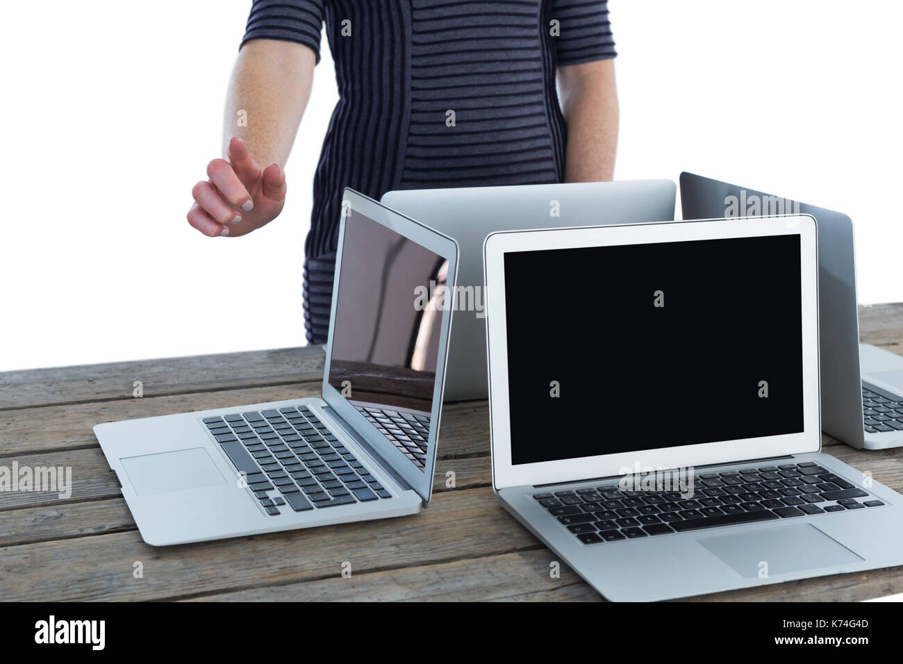 Den mittleren Abschnitt der Geschäftsfrau über Schnittstelle von Laptops am Tisch vor weißem Hintergrund Stockfoto