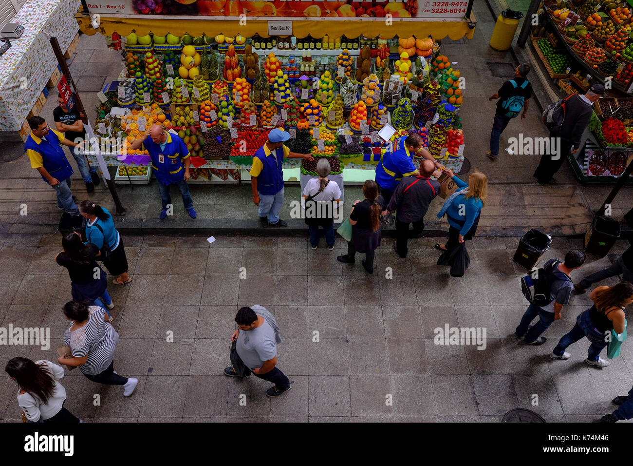 Das Leben im Mercado Municipal in Sao Paulo, Brasilien mit Verkäufern und Kunden rund um einen Obst- und Gemüsestände, Menschen zu Fuß vorbei Stockfoto