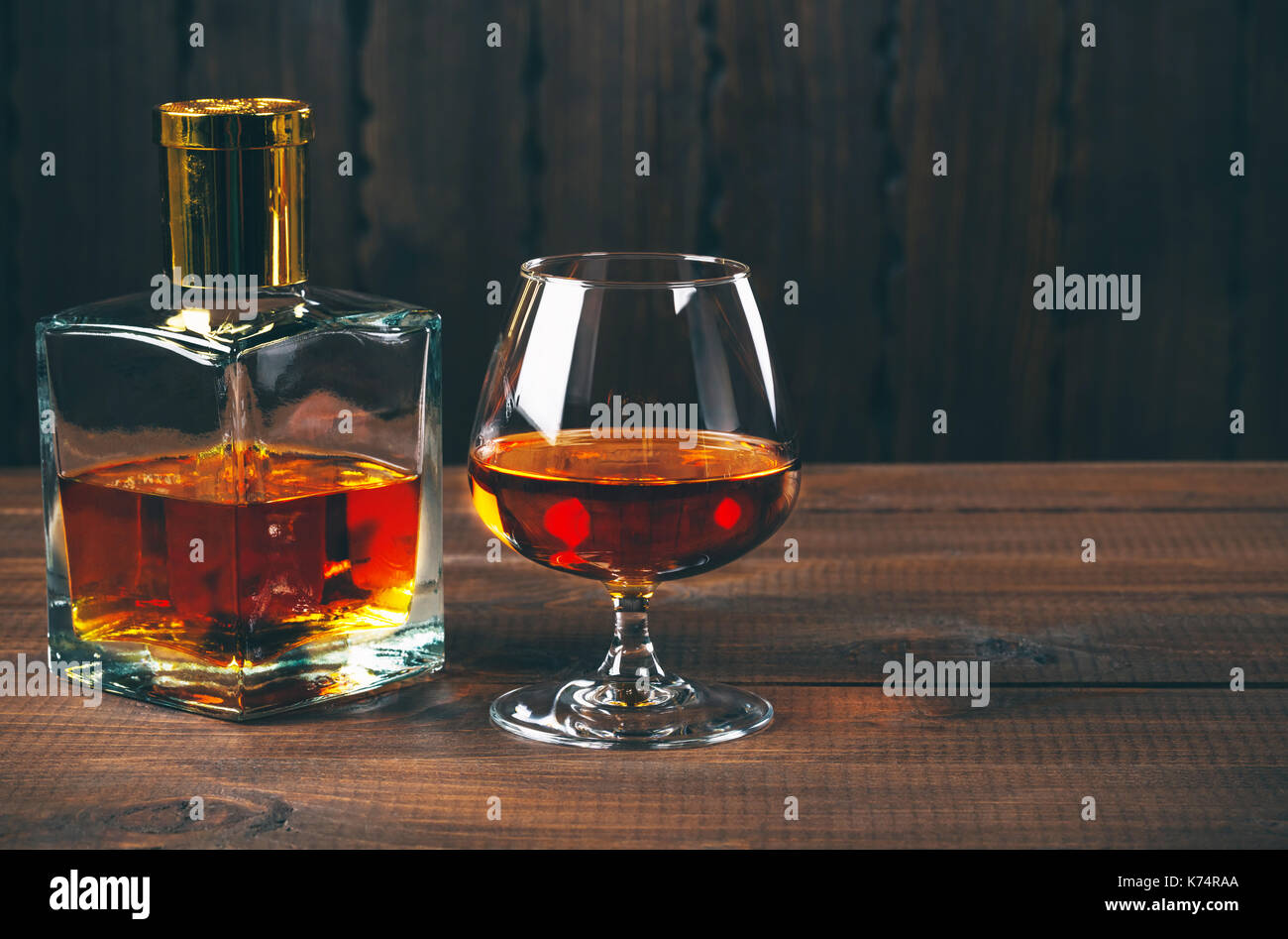 Glas Brandy oder Cognac und Flasche auf dem Holztisch. Stockfoto