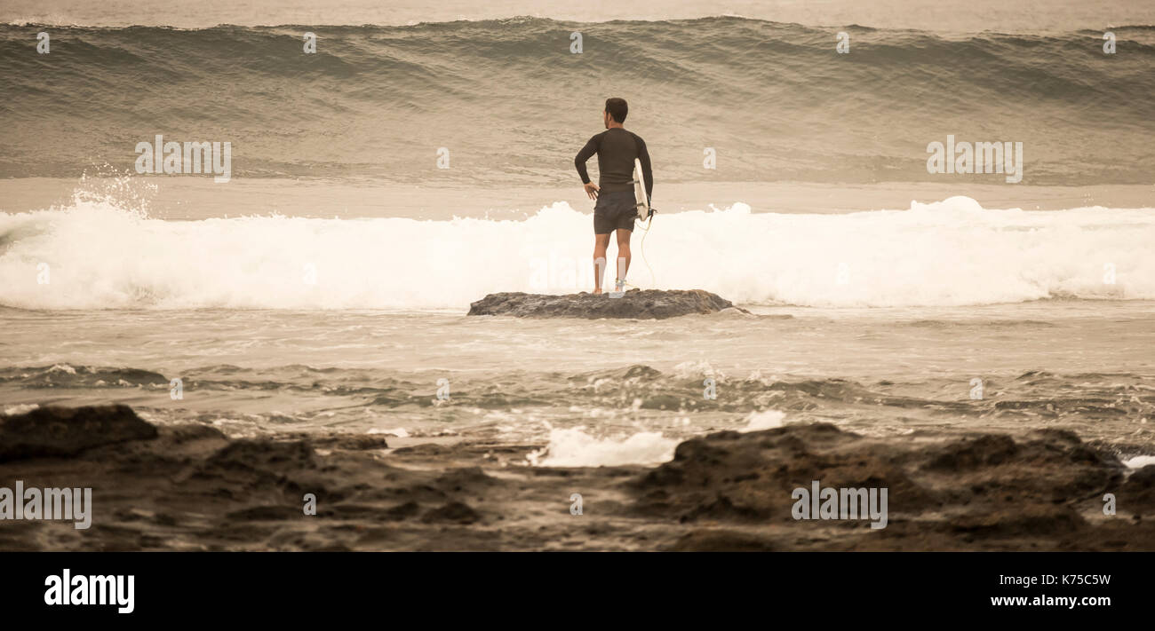 Surfer mit Surfbrett wartet auf eine Welle zu, bevor sie brechen. Stockfoto