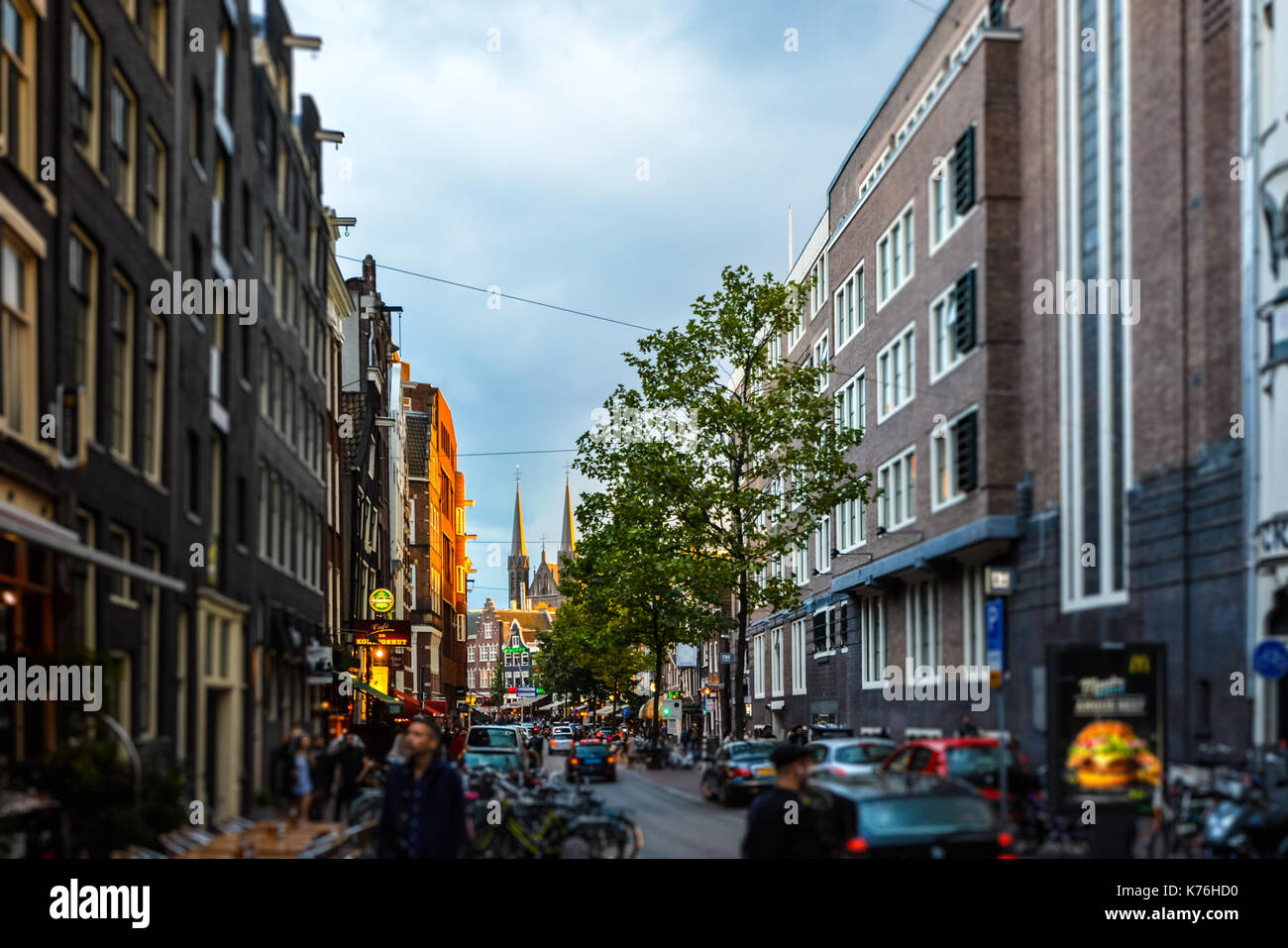 Viel befahrenen Straße in Amsterdam mit dem historischen Zentrum und eine Kirche mit Türmen, die im Hintergrund die Sonne untergeht Stockfoto
