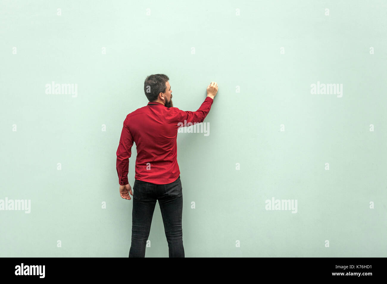 Junge Erwachsene Geschäftsmann Malerei auf graue Wand. Studio shot Stockfoto