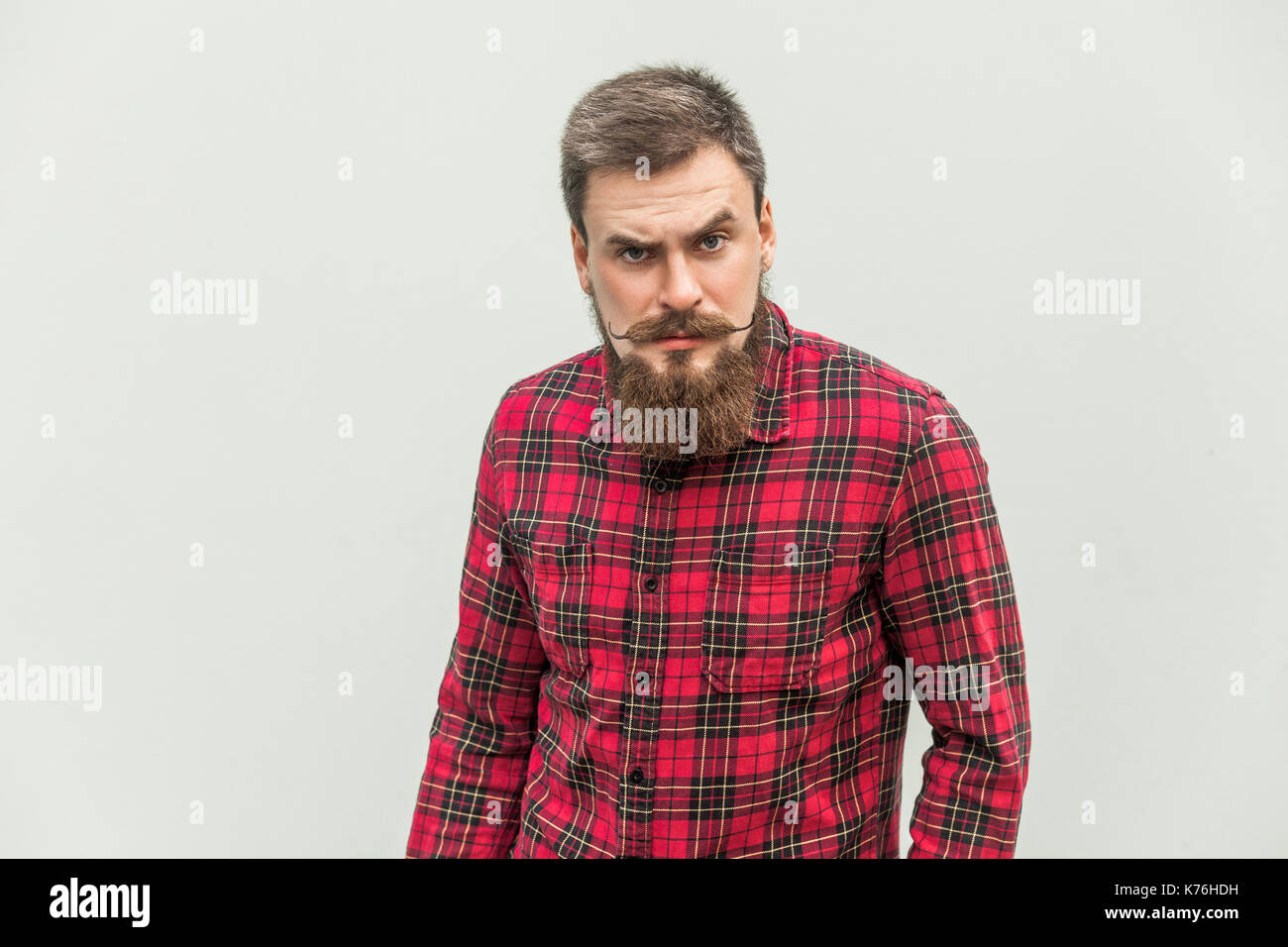 Wütend, aggressiv. Gut aussehender Geschäftsmann mit Bart und Schnurrbart Lenker an Kamera mit Verärgerten Gesicht. studio Shot, auf grauem Hintergrund. Stockfoto