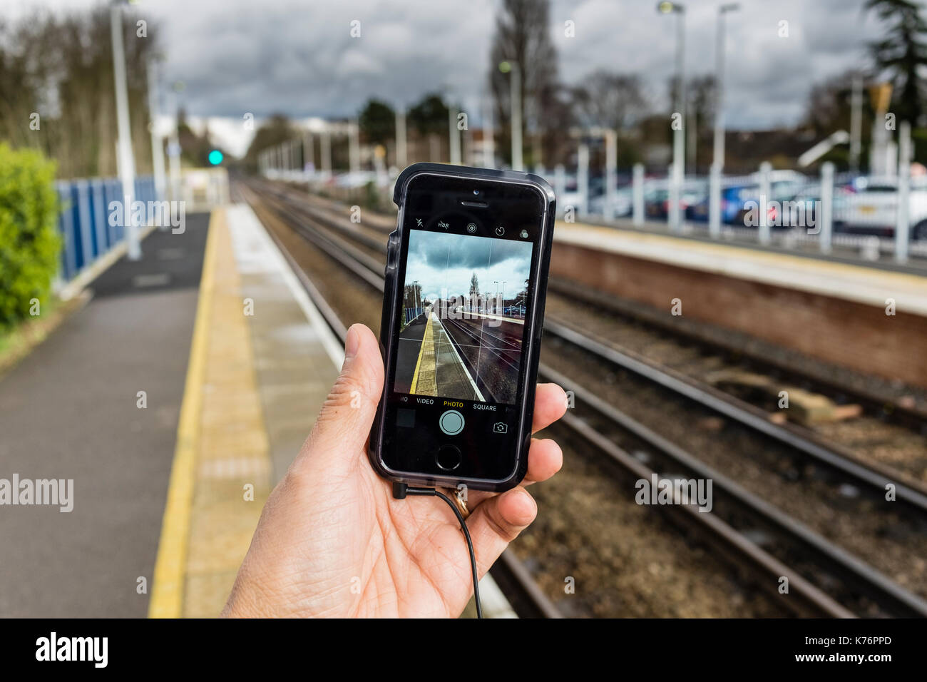 Ein männlicher Fotos machen und die Bahn mit einem iPhone SE Smartphone, Großbritannien Stockfoto