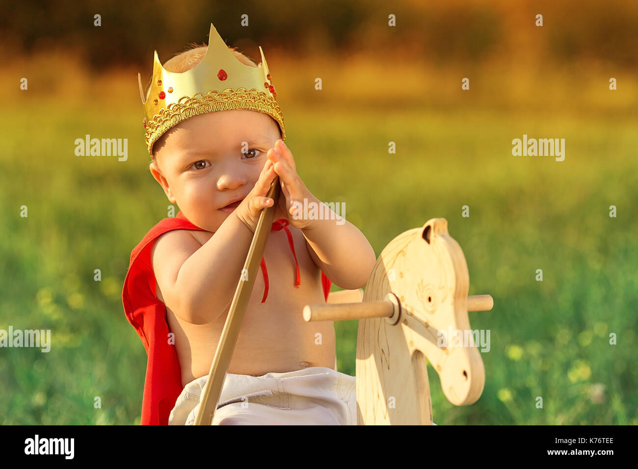 Kleine Prinz mit einer Krone auf dem Kopf und in einem roten Regenmantel. Große portrait Der kleine König. Stockfoto