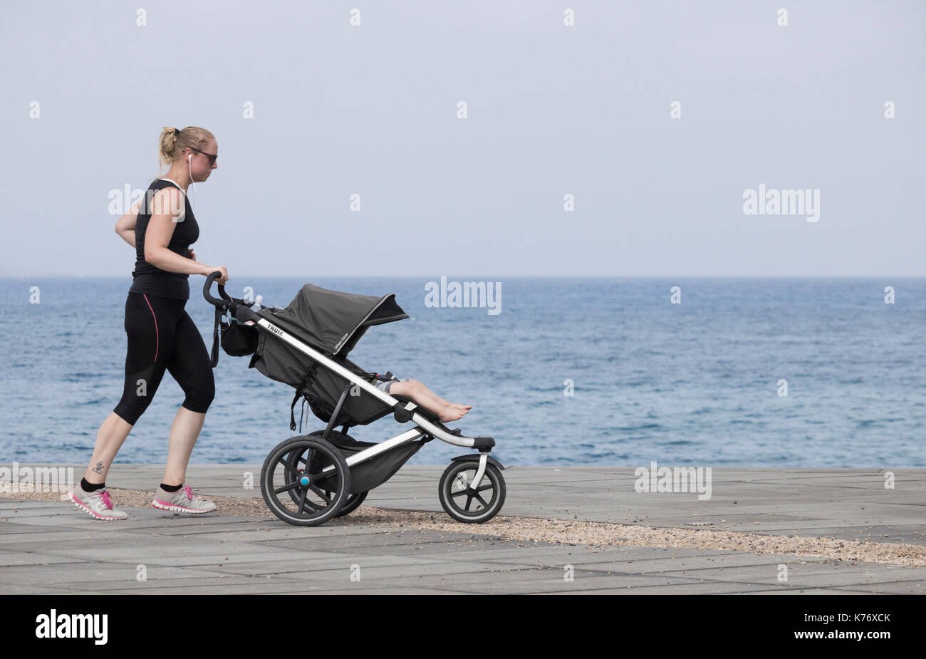 Frau joggen mit Baby/Kind im Kinderwagen / Buggy in Spanien Stockfoto