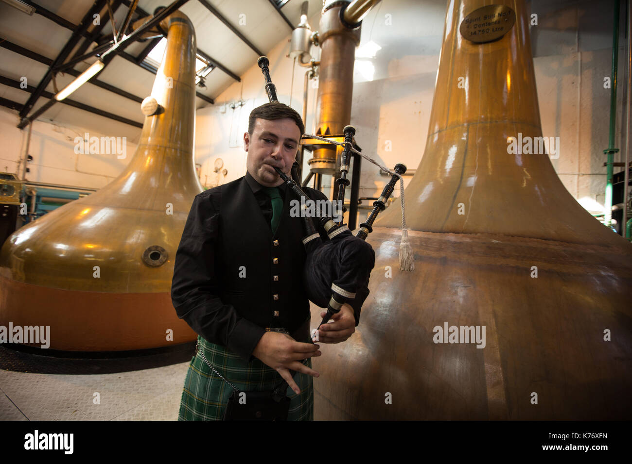 Bowmore Whisky Distillery mit Dudelsackspieler, Bowmore, in Schottland, am 15. September 2017. Stockfoto