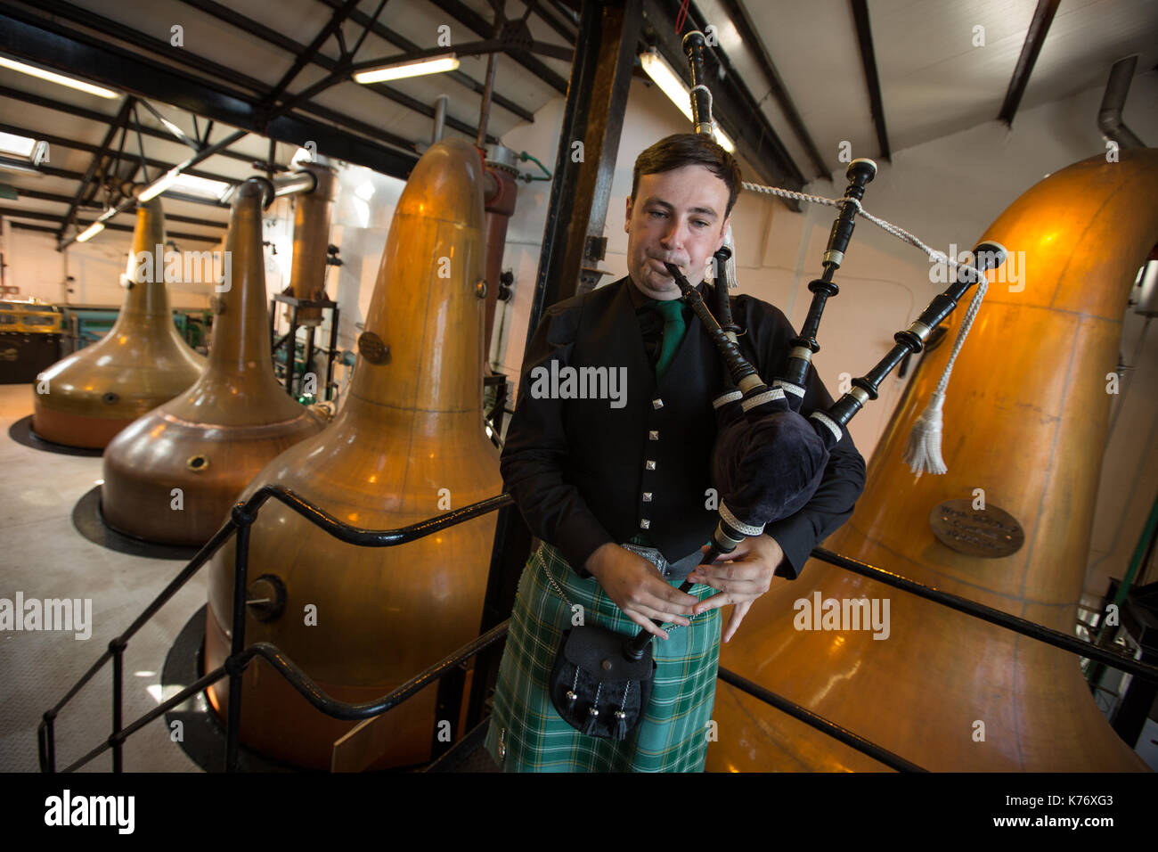 Bowmore Whisky Distillery mit Dudelsackspieler, Bowmore, in Schottland, am 15. September 2017. Stockfoto