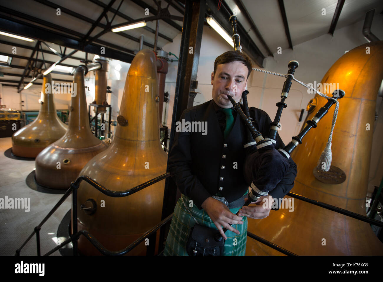 Bowmore Whisky Distillery mit Dudelsackspieler, Bowmore, in Schottland, am 15. September 2017. Stockfoto