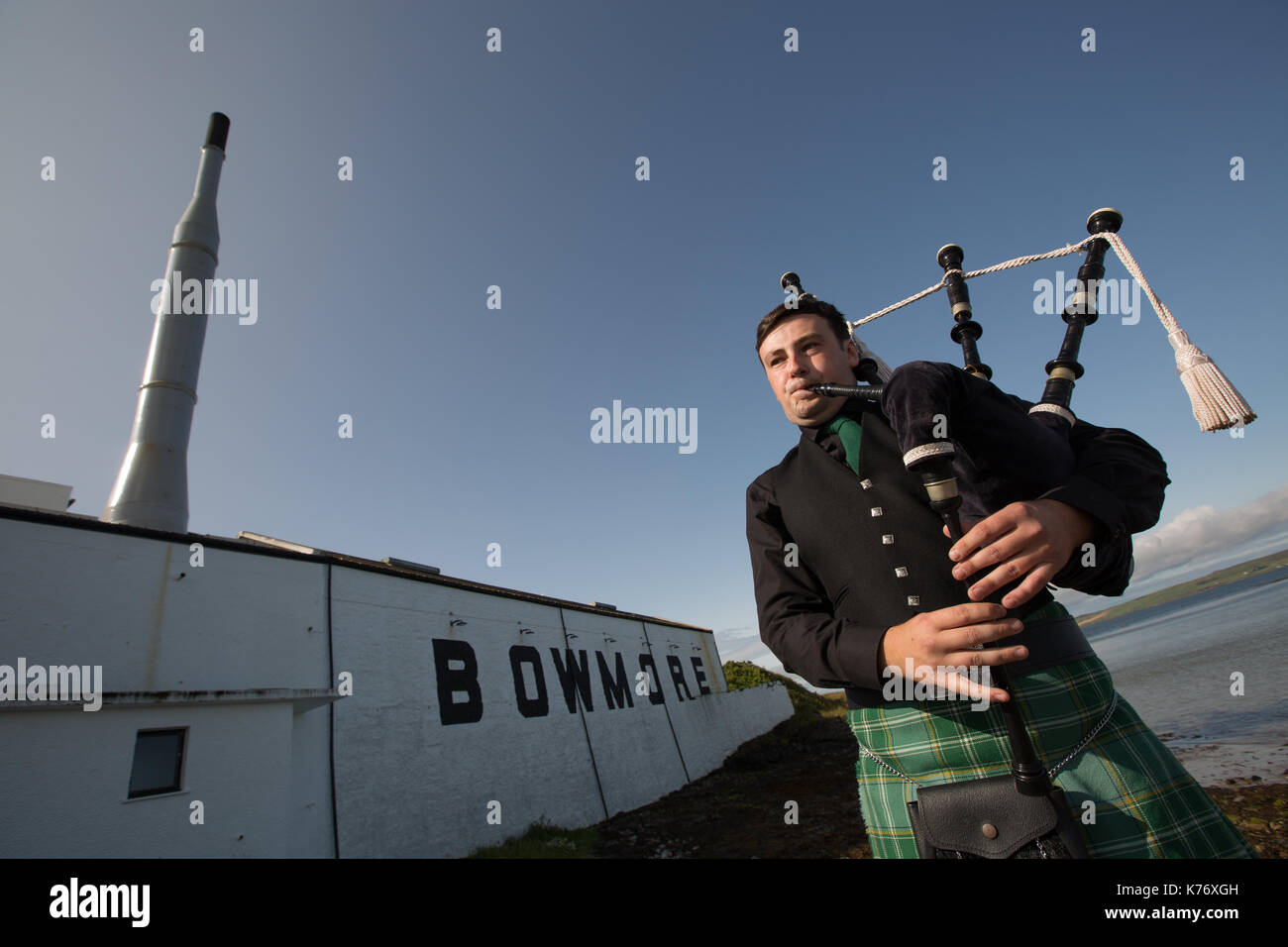 Bowmore Whisky Distillery mit Dudelsackspieler, Bowmore, in Schottland, am 15. September 2017. Stockfoto