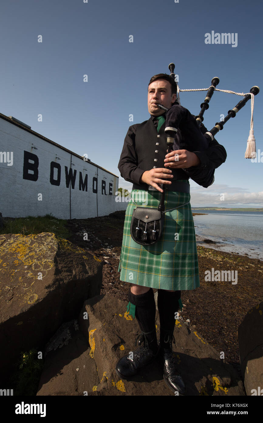 Bowmore Whisky Distillery mit Dudelsackspieler, Bowmore, in Schottland, am 15. September 2017. Stockfoto