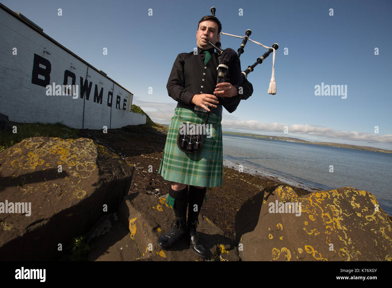 Bowmore Whisky Distillery mit Dudelsackspieler, Bowmore, in Schottland, am 15. September 2017. Stockfoto