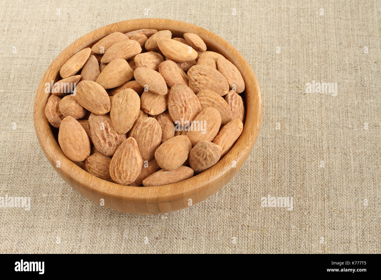 Gesalzene Mandeln in Bambusschüssel auf groben Leinentuch groß geschält Stockfoto