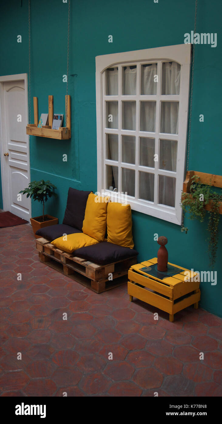 Sofa mit rustikalen Holzbrettern, mit gelben und braunen Kissen an einer grünen Wand in einem Haus Stockfoto