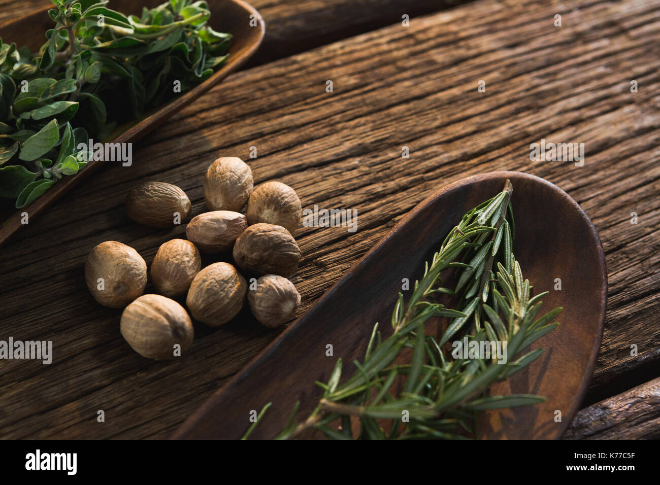 Nahaufnahme der Muskatnüsse und Rosmarin Kräuter auf einem Holztisch Stockfoto