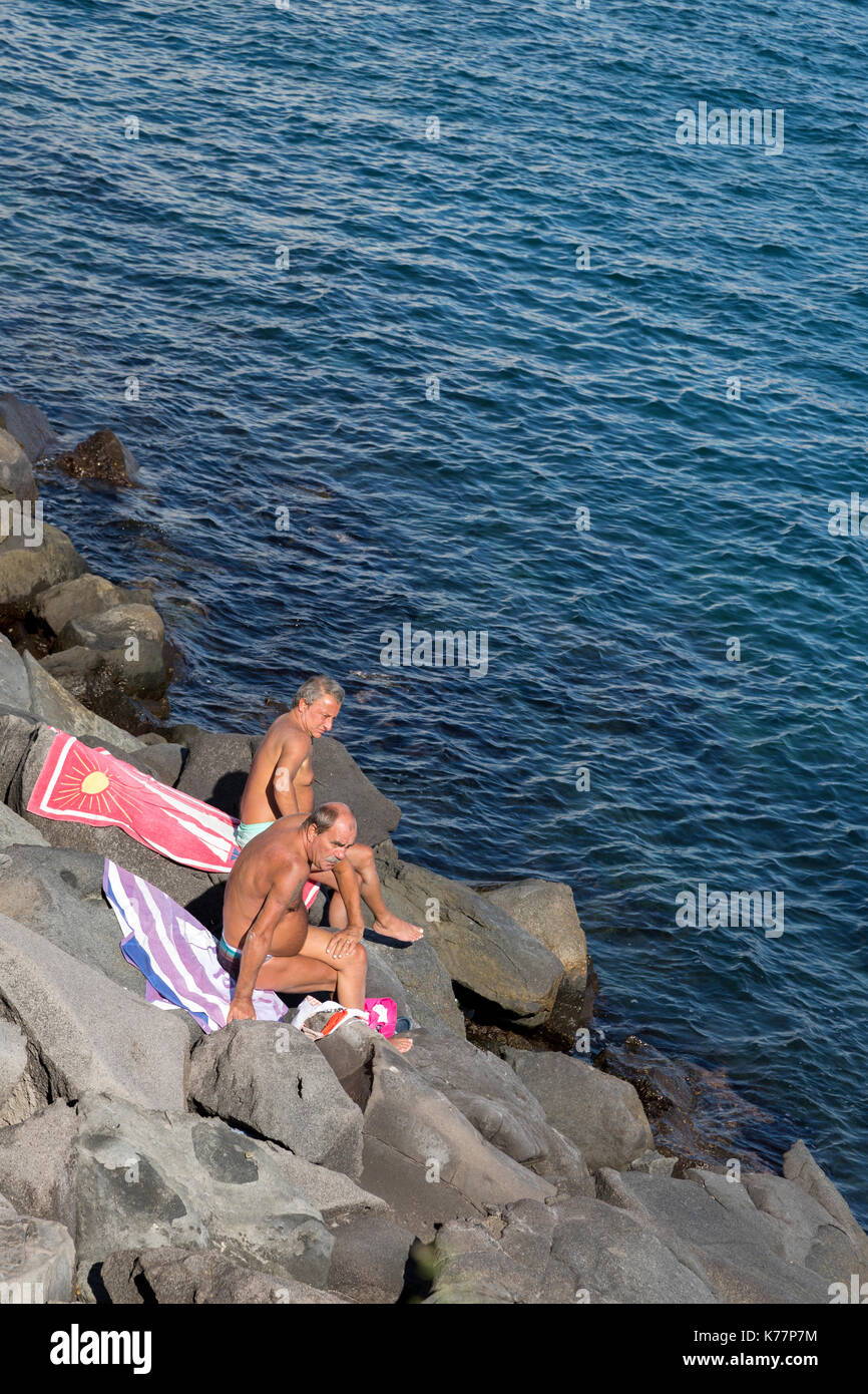 Ältere Männer Sonnenbaden auf den Felsen an der Küste von Italien, Golf von Neapel. Stockfoto