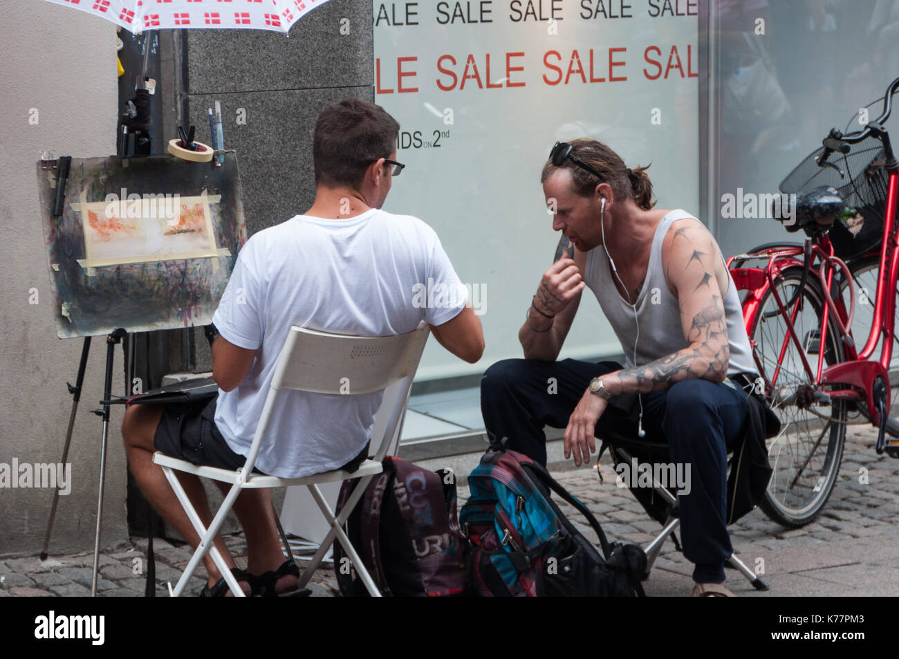 2 Männer sprechen über ein Gemälde an der Straße von Kopenhagen. Stockfoto