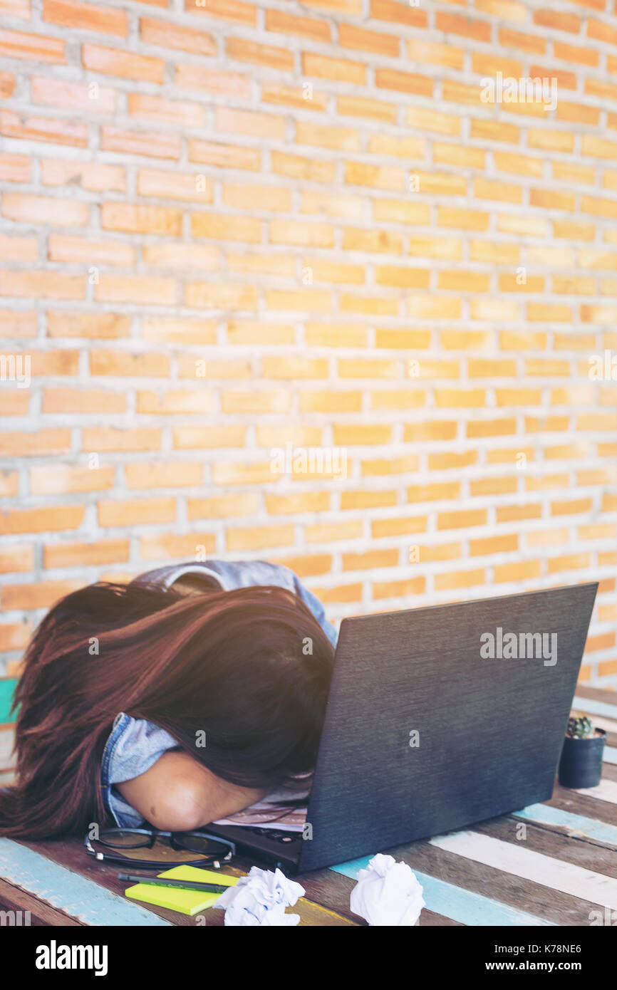 Nahaufnahme der jungen Frauen Business ist Gefühl Belastung mit ihr Arbeiten am Schreibtisch. geringe Tiefenschärfe, selektiver Fokus auf Kopf. vintage Tone, Sonnenlicht eff Stockfoto