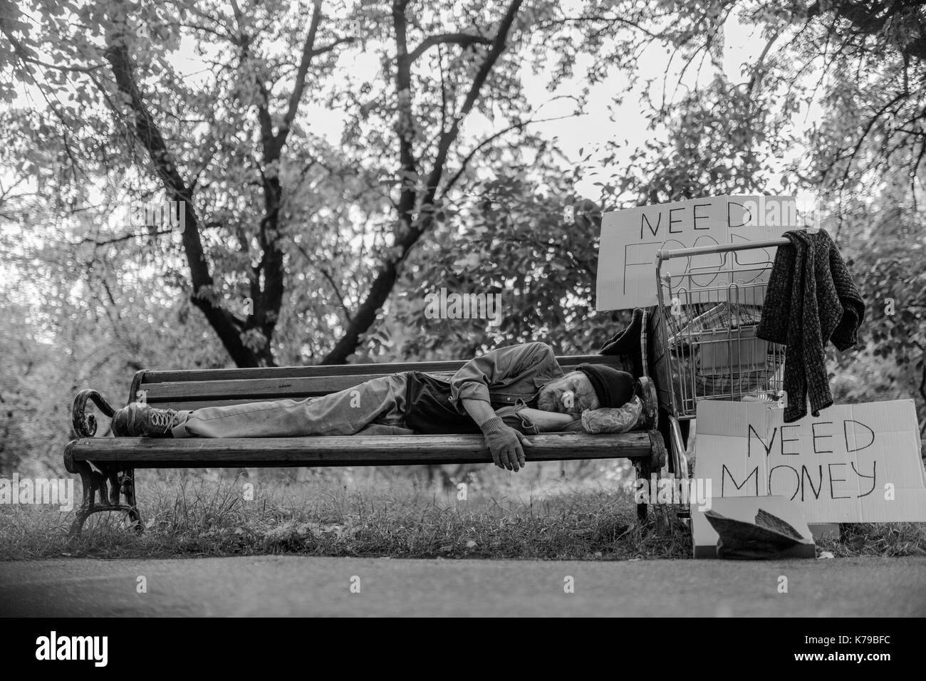 Schwarz-weiß-Porträt von Obdachlosen Mann lag auf der Bank. Stockfoto