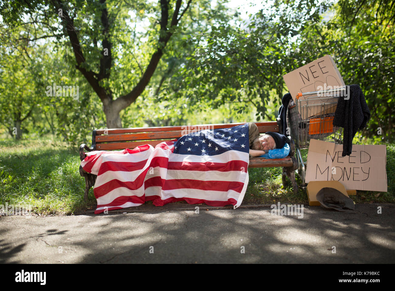 Anzeigen eines Obdachlosen liegen auf der Werkbank mit USA-Flagge bedeckt. Stockfoto