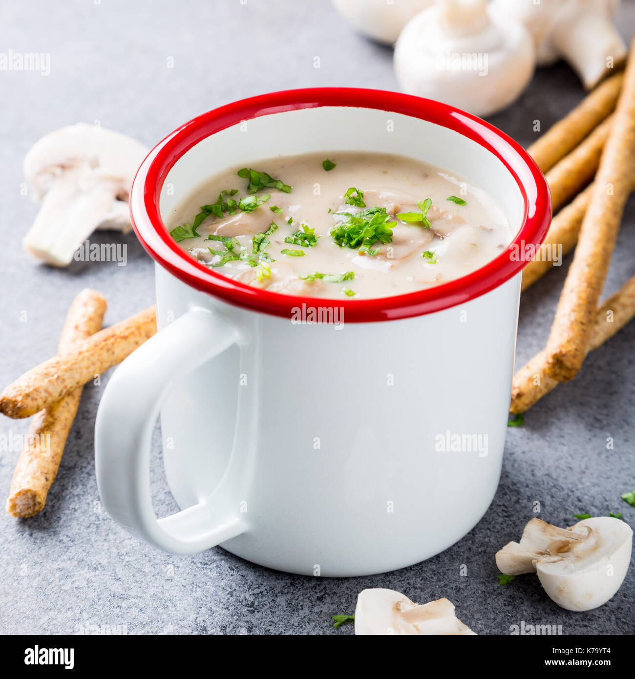 Weiß Emaille Tasse mit köstlichen hausgemachten Pilzen champignons Suppe mit Petersilie. Gesunde Ernährung Konzept. Stockfoto