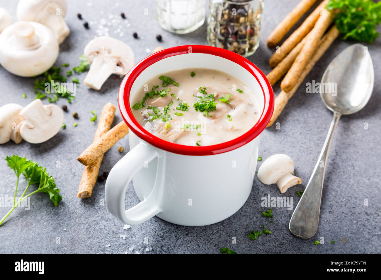 Weiß Emaille Tasse mit köstlichen hausgemachten Pilzen champignons Suppe mit Petersilie. Gesunde Ernährung Konzept. Stockfoto