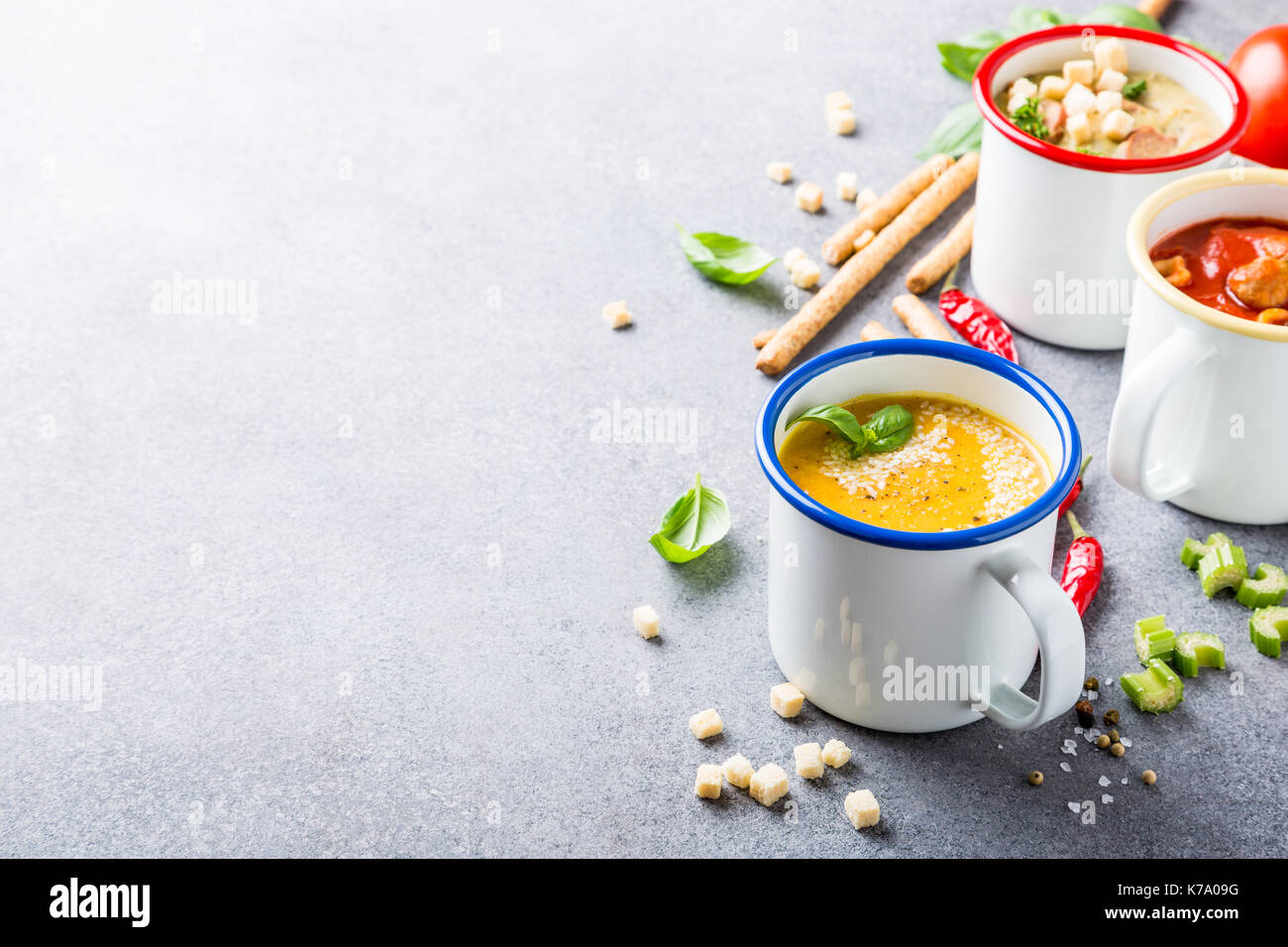 Verschiedene köstliche hausgemachte Suppen in Emaille Becher mit Zutaten. Gesunde Ernährung Konzept mit kopieren. Stockfoto