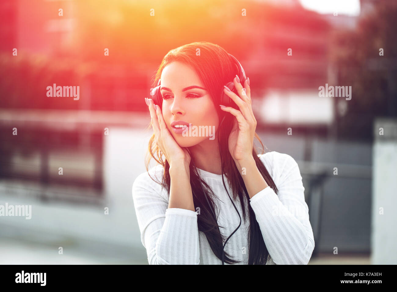 Junge brünette Frau Hören von Musik über Kopfhörer outdoor im Sonnenuntergang Stockfoto