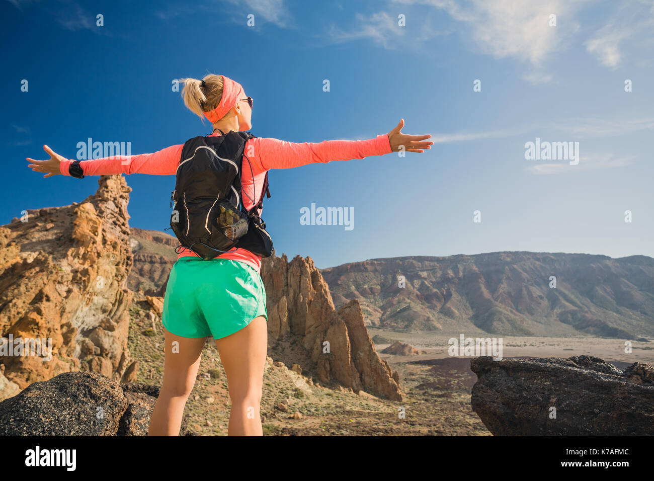 Frau Wanderer mit ausgestreckten Armen in den Bergen. Schönheit Läuferin, Hände hoch und inspirierende Landschaft auf Rocky Trail Wanderweg auf Teneriffa genießen. Stockfoto