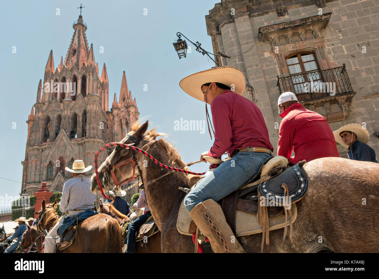 Cowboys auf dem Pferderücken reiten in den Jardin Allende vor der prunkvollen Parroquia de San Miguel Arc‡ngel Kirche während des ersten Tages der Feierlichkeiten zum mexikanischen Unabhängigkeitstag, bekannt als der Schrei der Dolores 15. September 2017 in San Miguel de Allende, Mexiko. Stockfoto