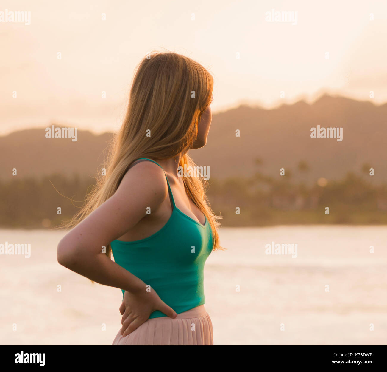 Nachdenkliche Frau mit der Hand auf den Hüften weg schauen beim Stehen auf See gegen Sky Stockfoto