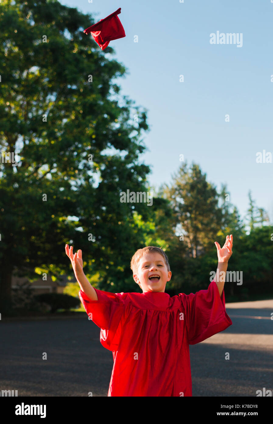 Portrait von Happy Boy an der Staffelung Kleid werfen mortarboard auf Fußweg Stockfoto