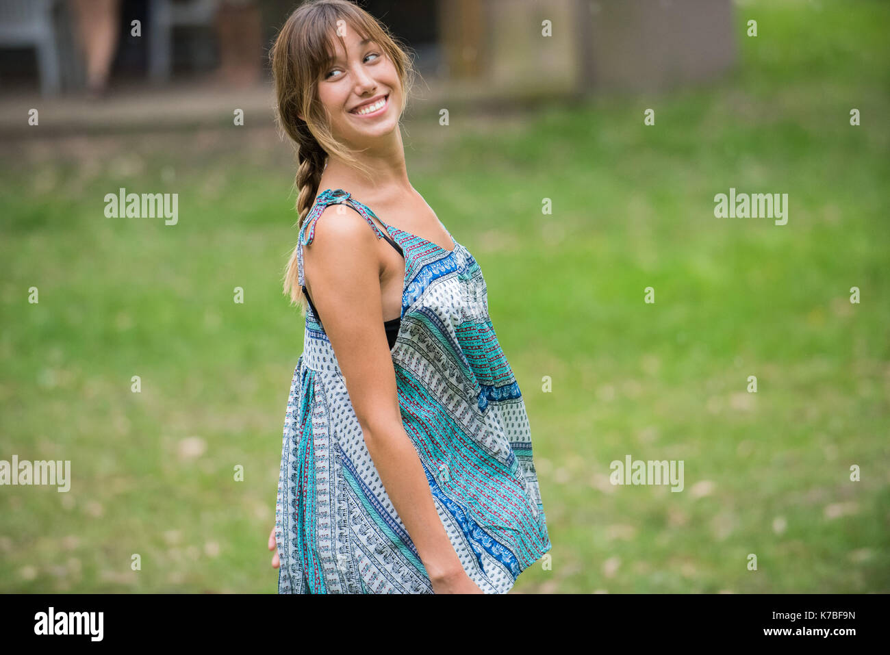 Junge Frau lächelnd über die Schulter im Freien Stockfoto