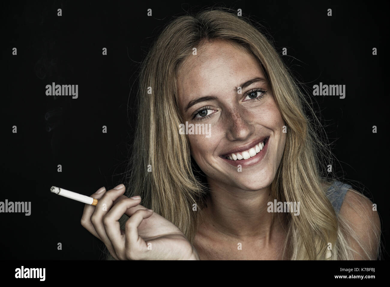 Junge Frau mit Zigarette und freundlich lächelnd, Porträt Stockfoto