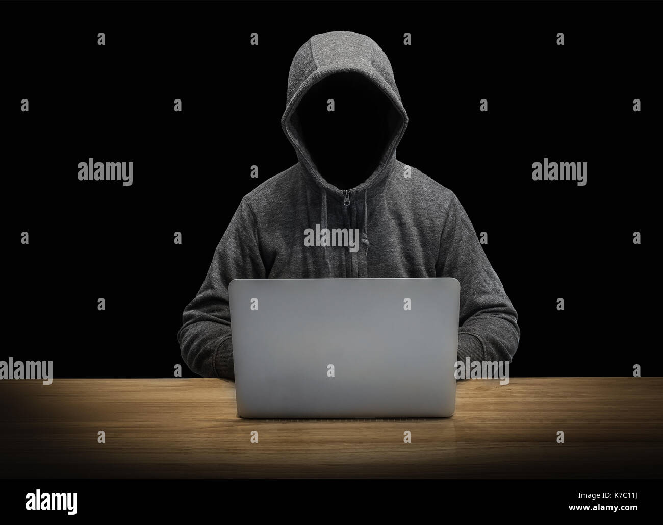 Mit Kapuze Mann mit leerem Gesicht Arbeiten mit Notebook isoliert auf Schwarz Stockfoto